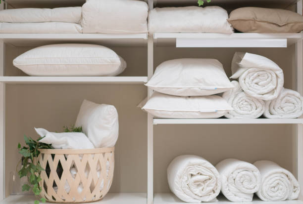 Neatly folded white towels and pillows are stored on shelves, emphasizing organization and freshness.